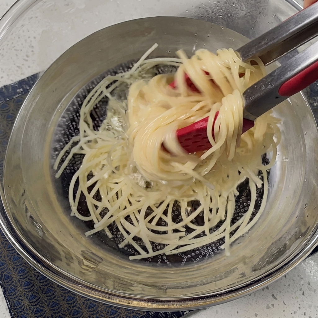 Ugotowane spaghetti odcedzane w metalowym durszlaku.