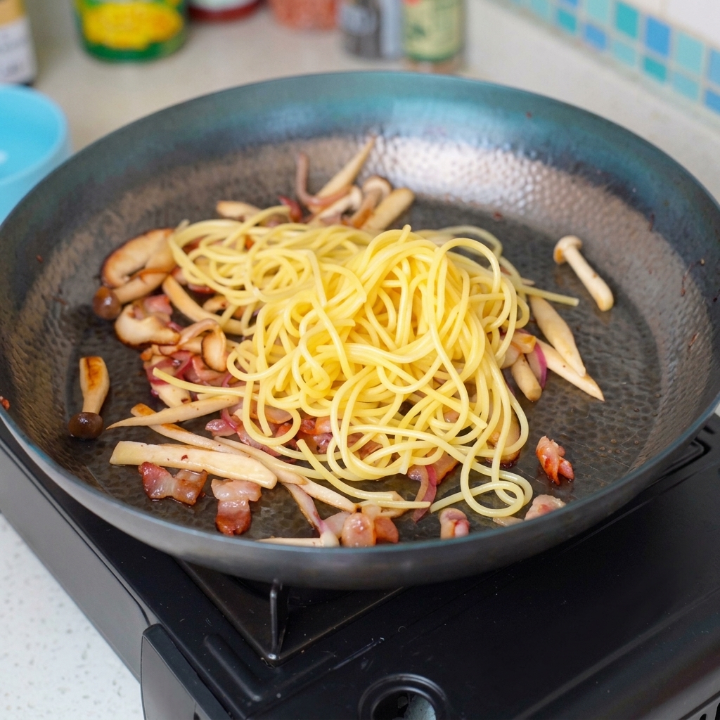 Makaron angel hair mieszany ze składnikami na patelni.