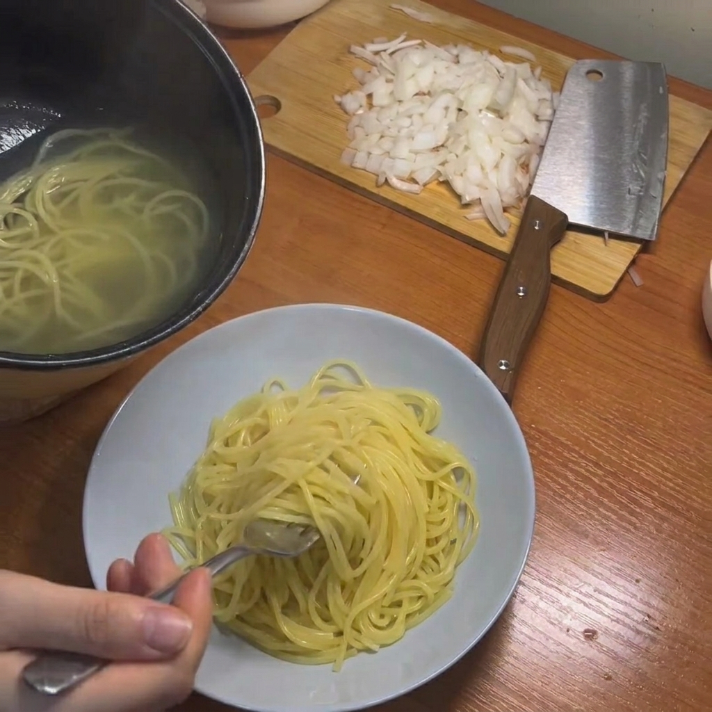 Ugotowane spaghetti wyjmowane z garnka za pomocą pałeczek.