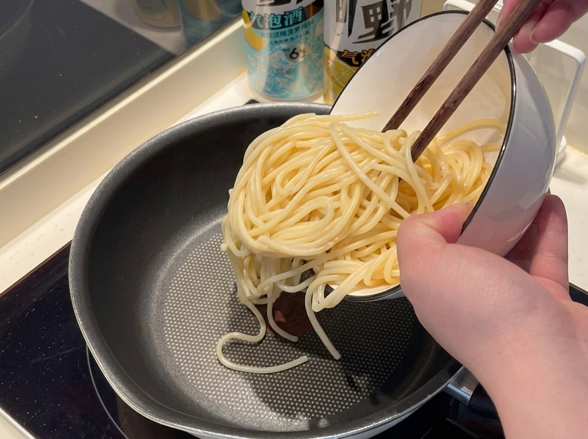 Nitki spaghetti wkładane do wrzątku w garnku.