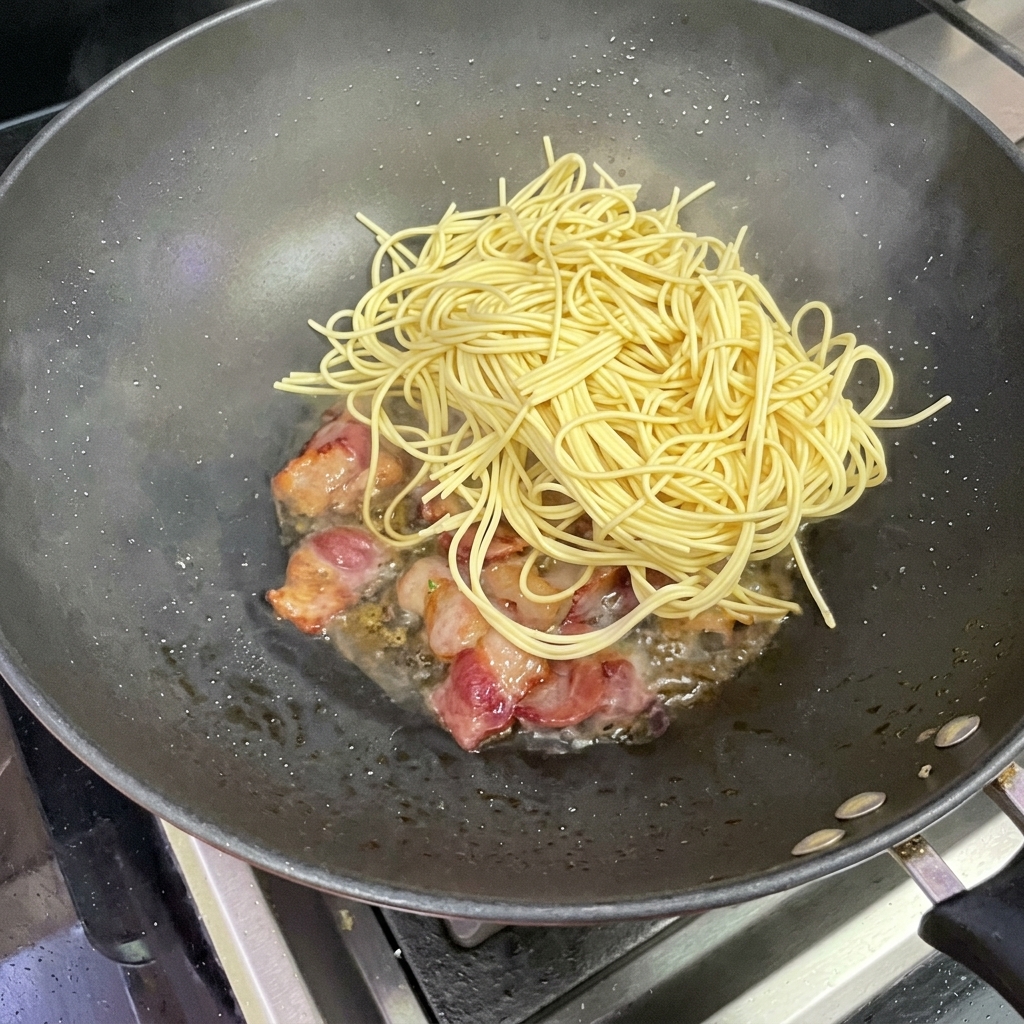 Makaron spaghetti dodawany do woka z boczkiem.