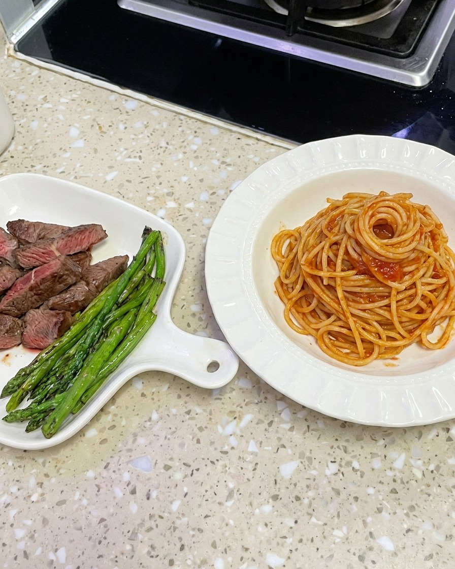 Spaghetti wyjmowane z woka szczypcami do ułożenia w białej misce.