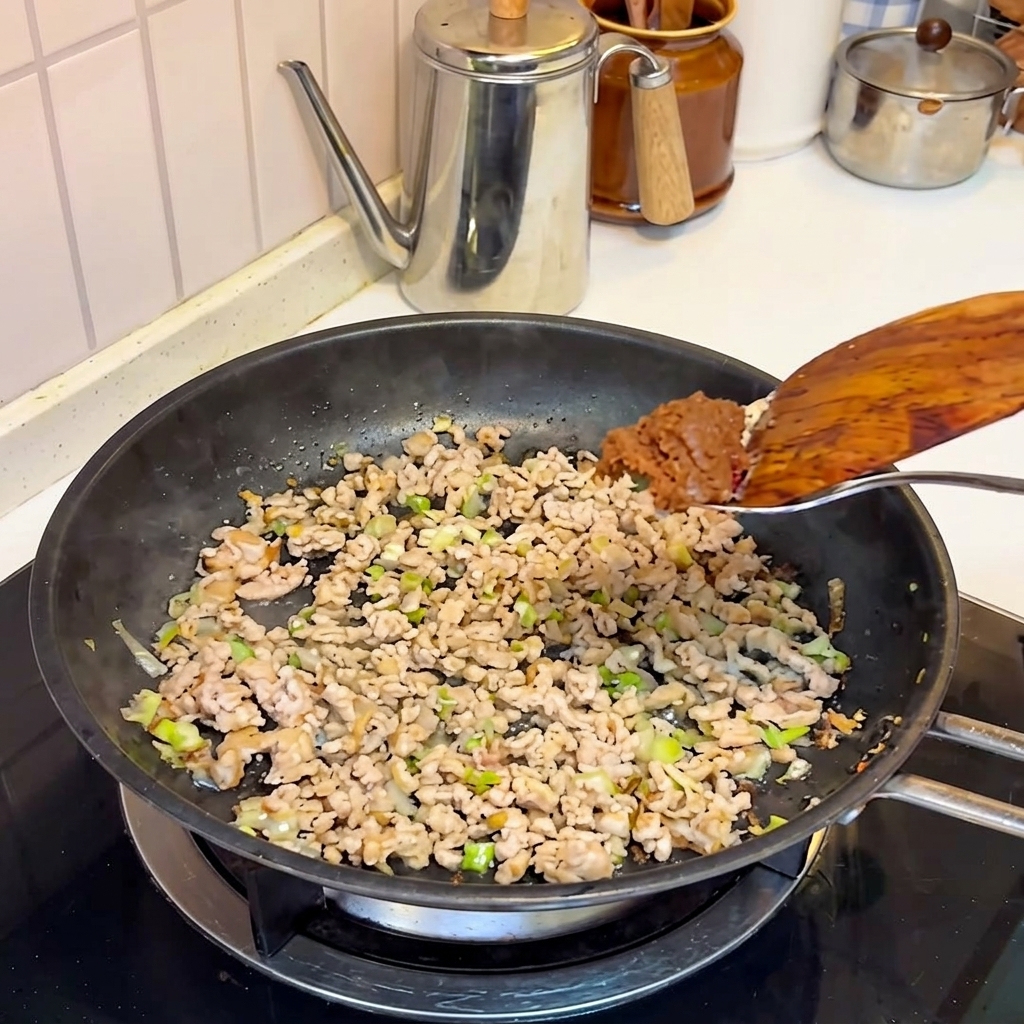 Pasta miso dodawana do podsmażonego mięsa na patelni.