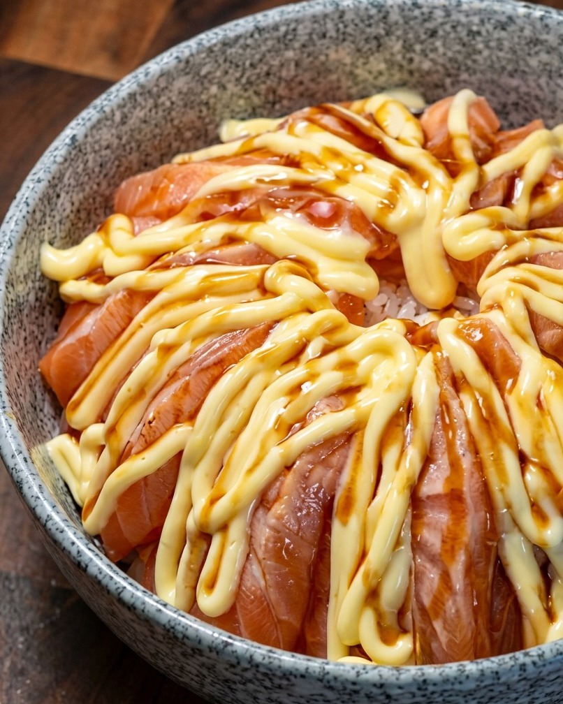 Miska ryżu z łososiem polana ciemnym sosem teriyaki na warstwie majonezu.