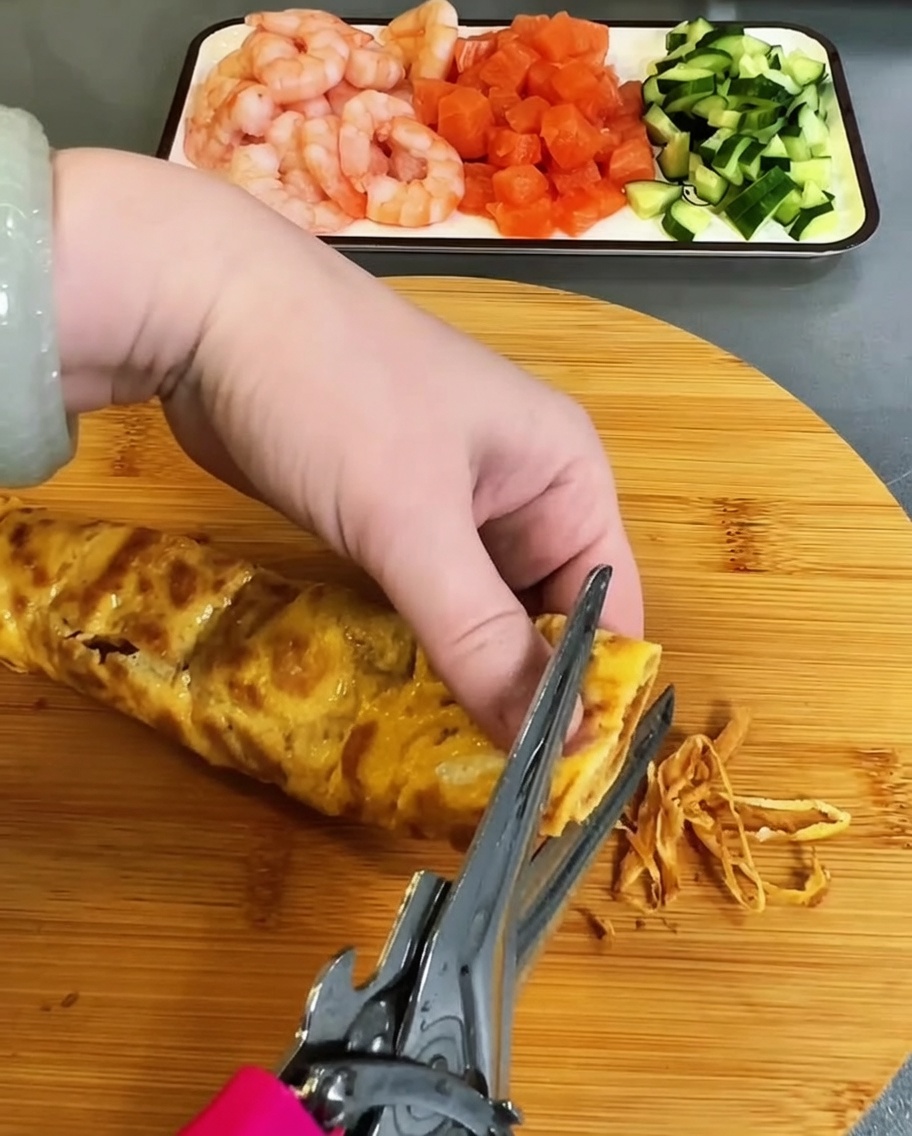 Usmażony omlet delikatnie cięty kuchennymi nożyczkami w cienkie paski.