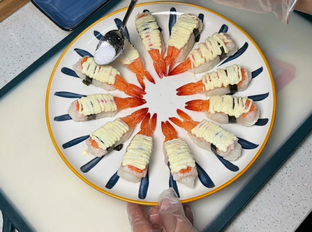 Łyżeczka posypująca cukrem sushi z majonezem na dekoracyjnym talerzu.