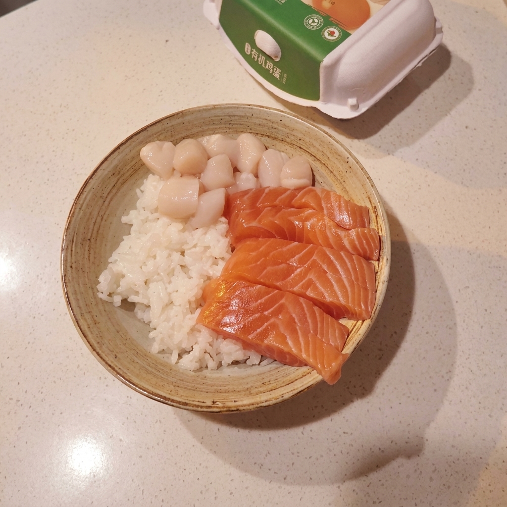 Miska wypełniona bazą z ryżu do sushi, zwieńczona starannym układem świeżego łososia, przegrzebków i surowych słodkich krewetek.