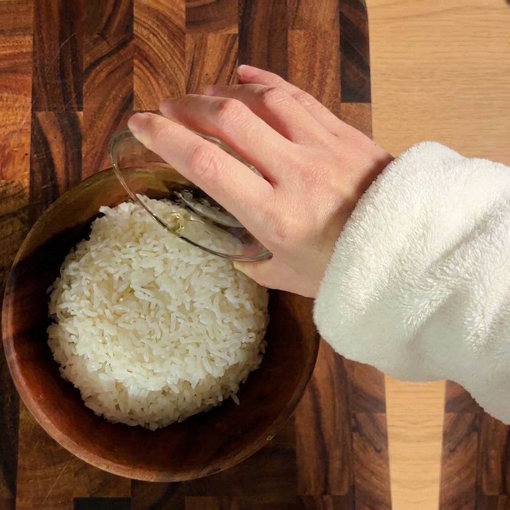 Ugotowany biały ryż doprawiany octem do sushi w drewnianej misce.