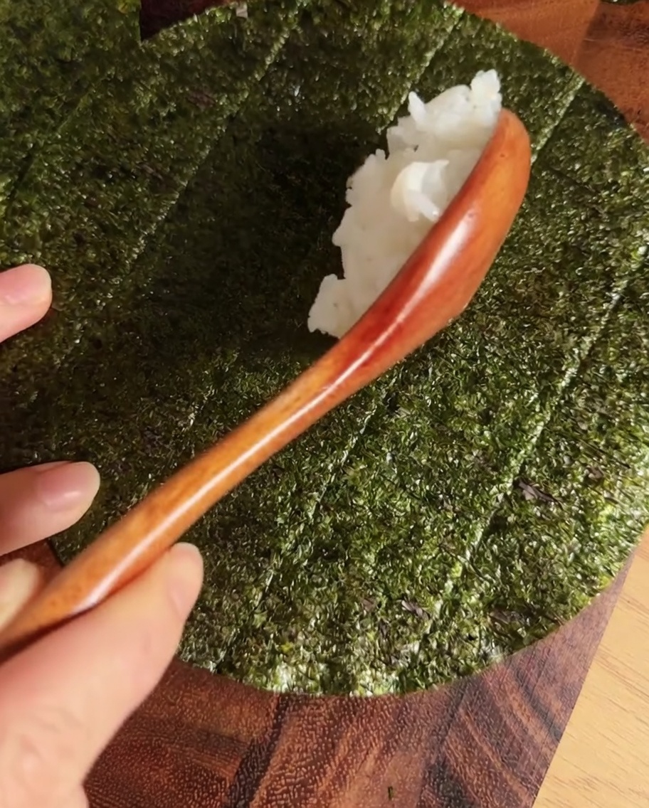 Pasek ryżu do sushi na środku okrągłego arkusza nori.