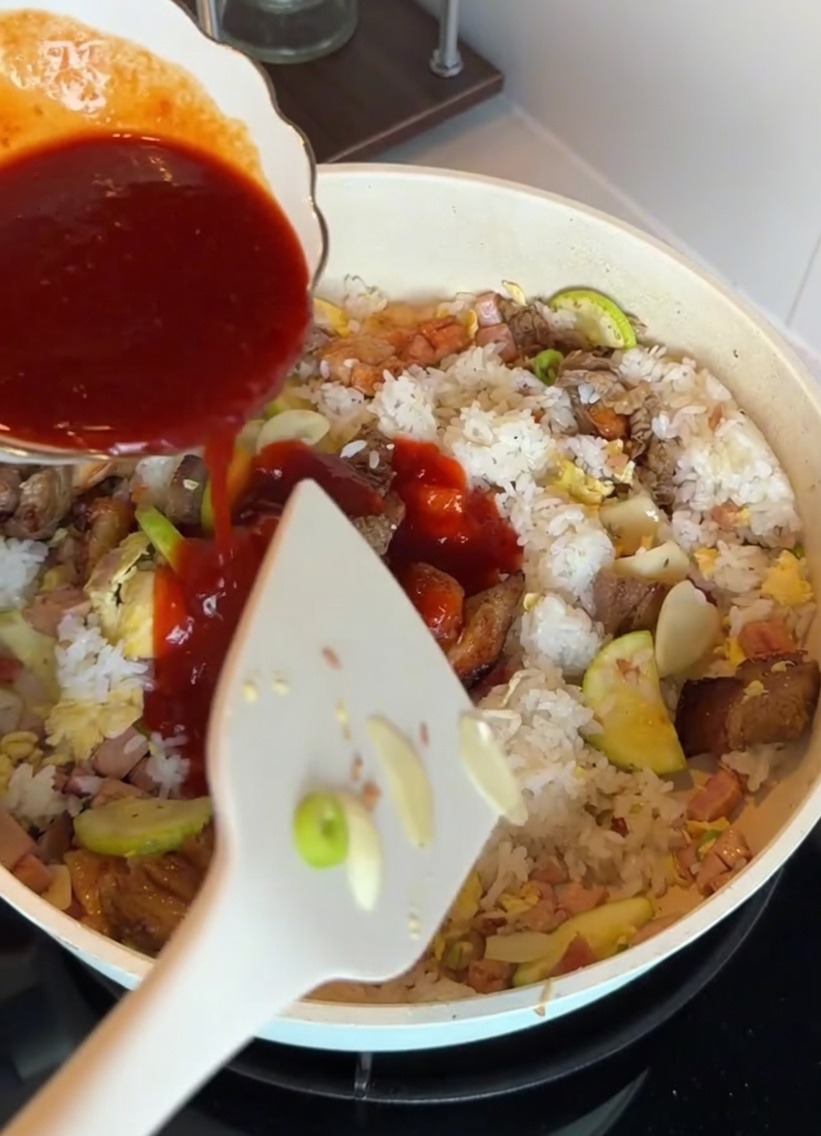 Koreański sos do bibimbap wlewany na ryż i pozostałe składniki na patelni.