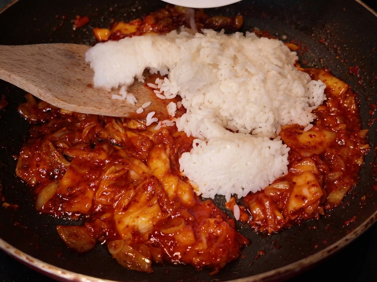 Drewniana łopatka dodająca ryż na patelnię z kimchi.