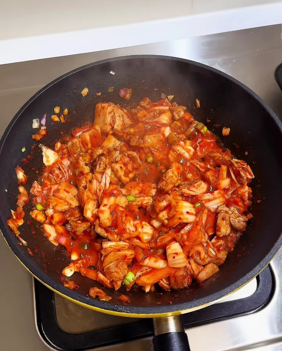 Ugotowany biały ryż dodawany do patelni z kimchi i boczkiem.
