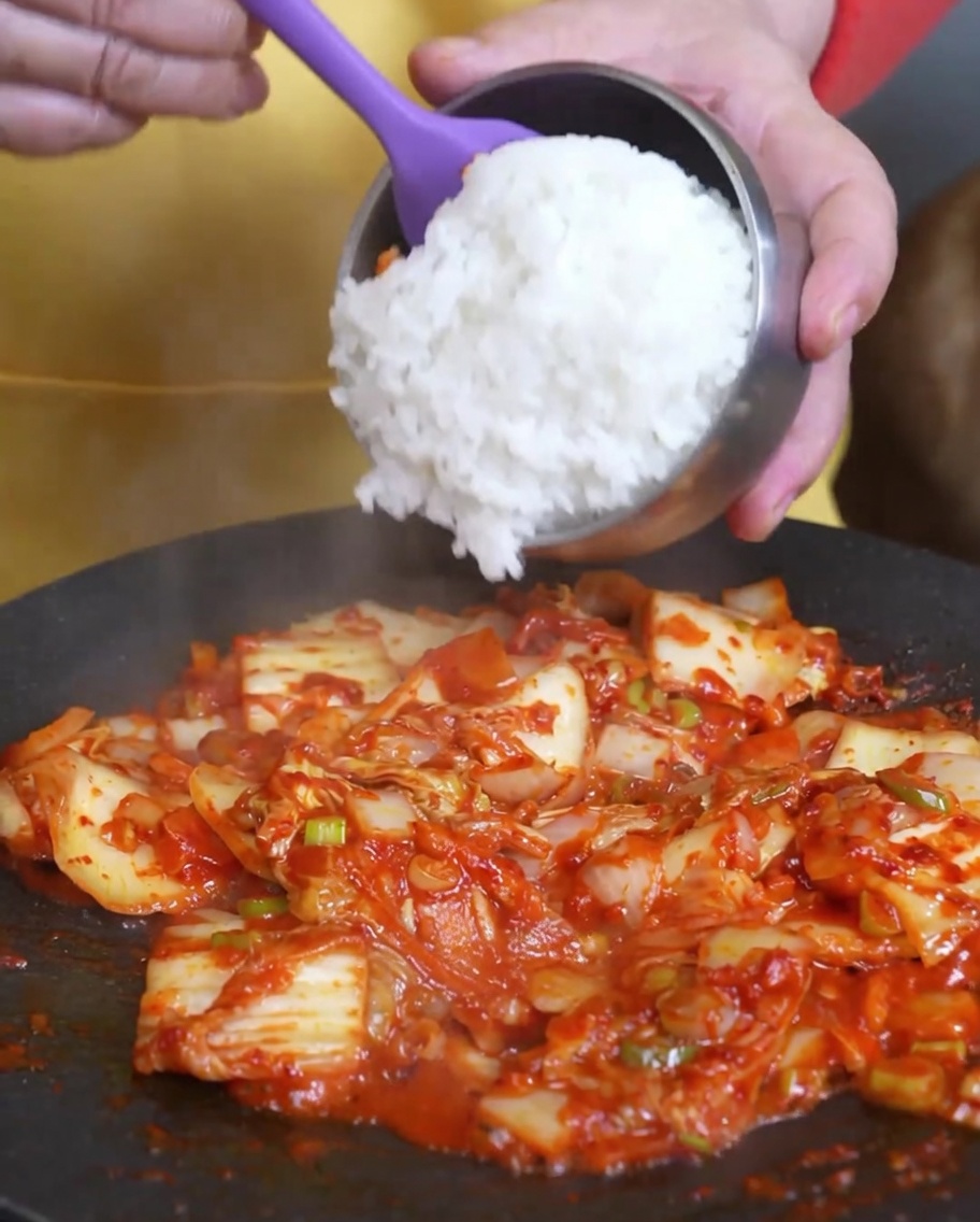 Ugotowany biały ryż dodawany do patelni ze smażonym kimchi.