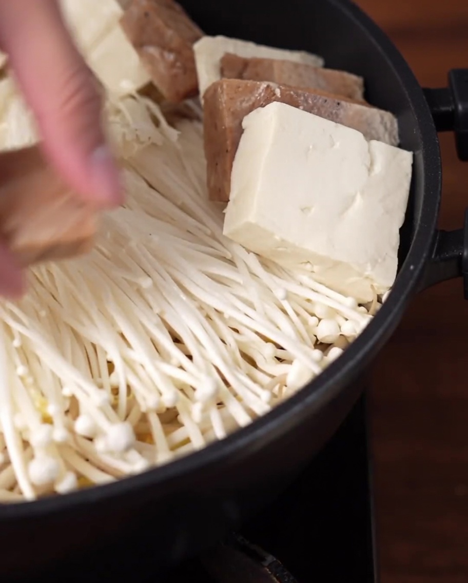 Plastry tofu i wegańskiej mielonki ułożone w okrągły wzór w garnku.