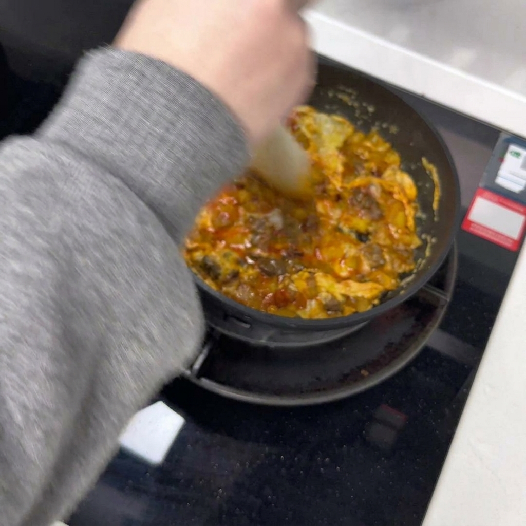 Łopatka dzieląca smażący się omlet na dwie połowy na patelni.
