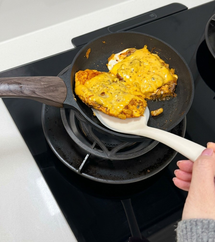 Łopatka podnosząca usmażony, serowy omlet z wołowiną w celu umieszczenia go w otwartej bułce.