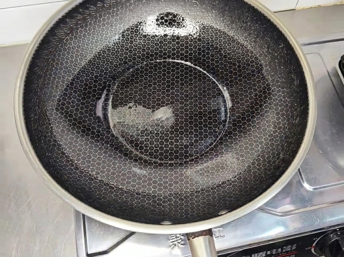 Kotlet z kurczaka smażący się na patelni na złoty kolor.