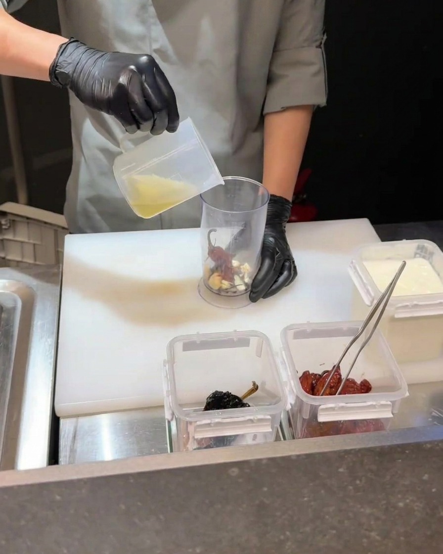 Blender ręczny miksujący chili, żółtko i płyn w pojemniku.