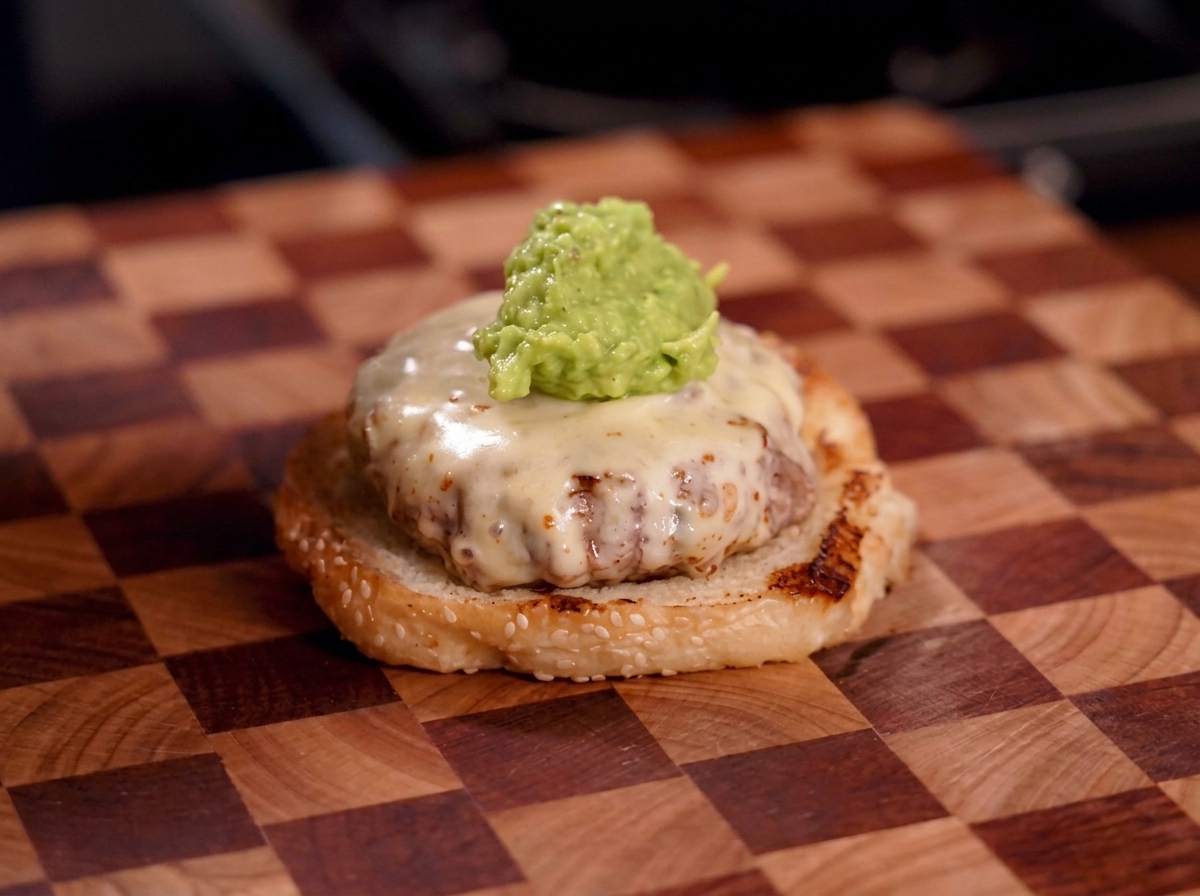 Duża porcja zielonego guacamole na burgerze z serem.