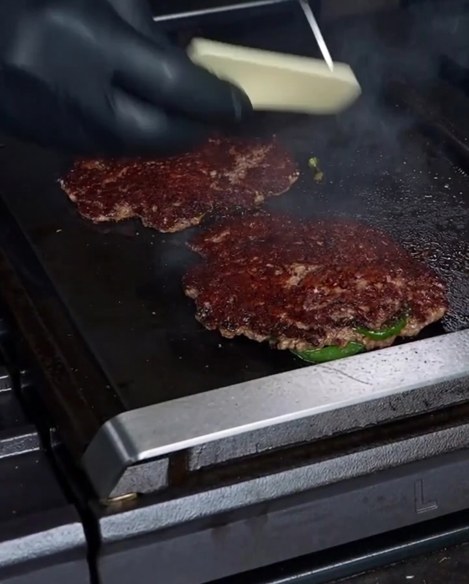 Kładzenie sera Havarti na usmażonym burgerze.