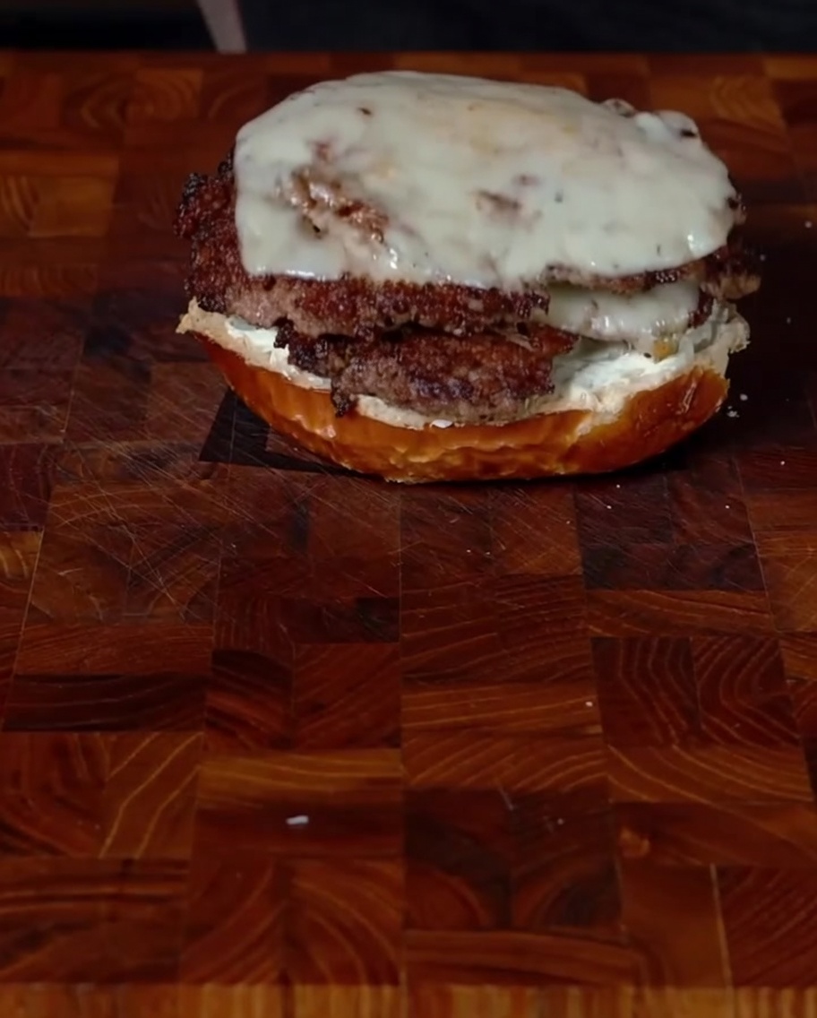 Układanie dwóch burgerów z serem na bułce.