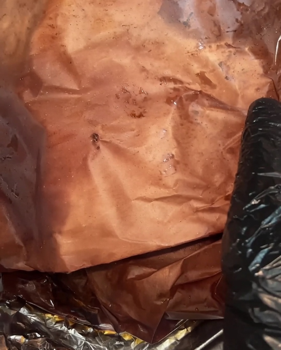 W pełni upieczony mostek po odwinięciu, prezentujący ciemną, wilgotną skórkę oraz bogate soki zbierające się w papierze.