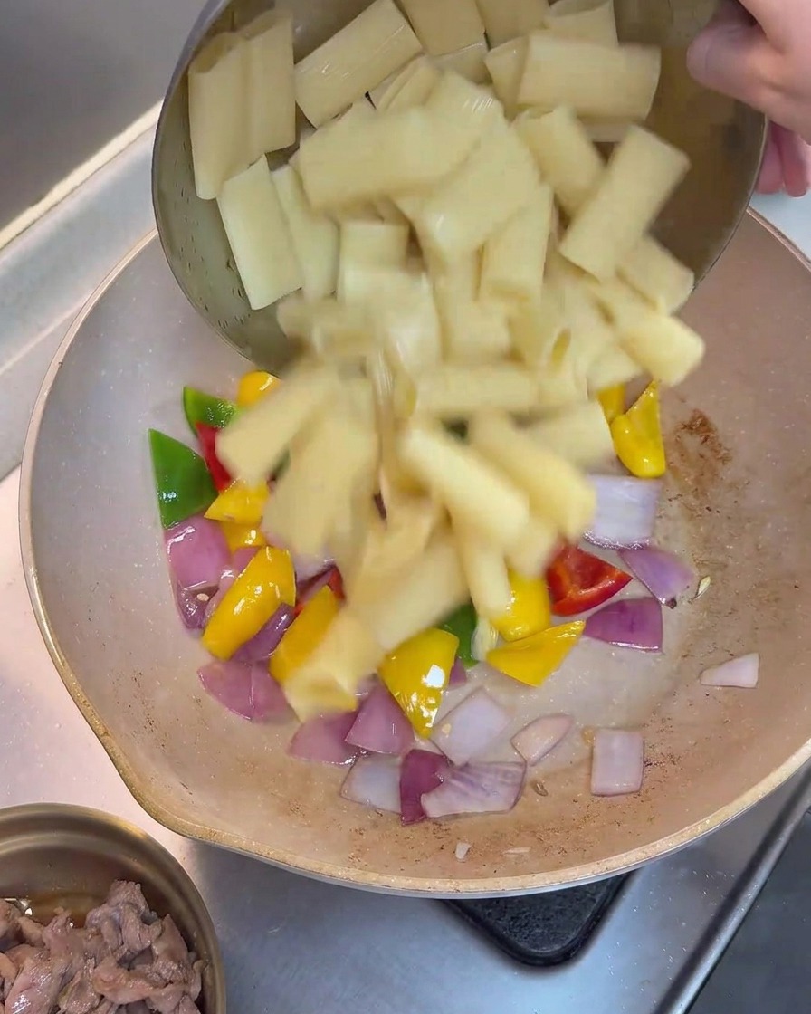 Ugotowane rigatoni dodawane na patelnię do warzyw.