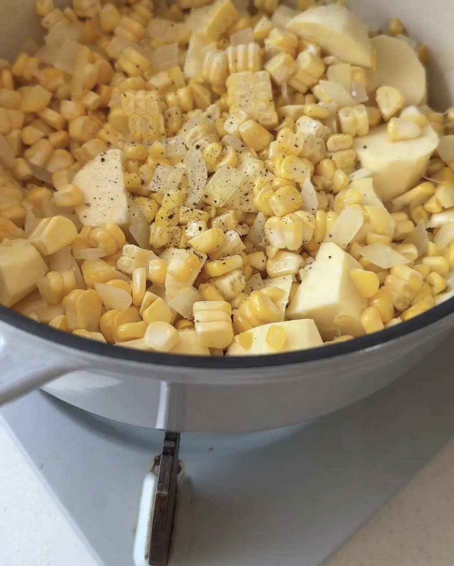 Czarny pieprz świeżo mielony nad mieszanką kukurydzy, cebuli i batata w garnku.