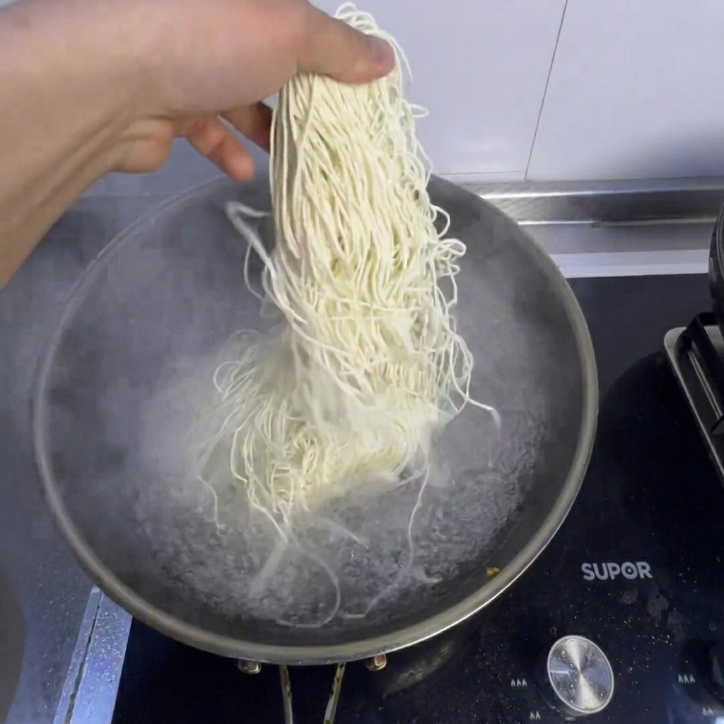 Makaron i świeży bok choy gotowane w garnku z wrzącą wodą.