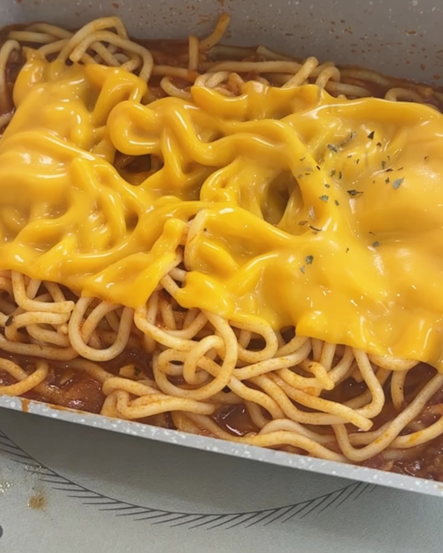 Spaghetti z roztopionym serem, posypane dla dekoracji suszoną pietruszką.