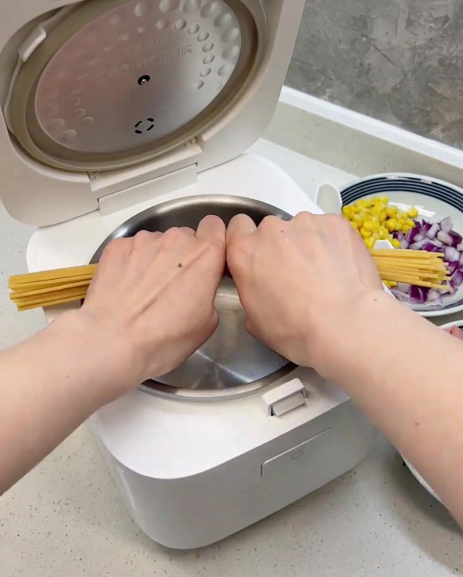 Makaron spaghetti przełamany na pół, równo ułożony w czystej misie szybkowaru.