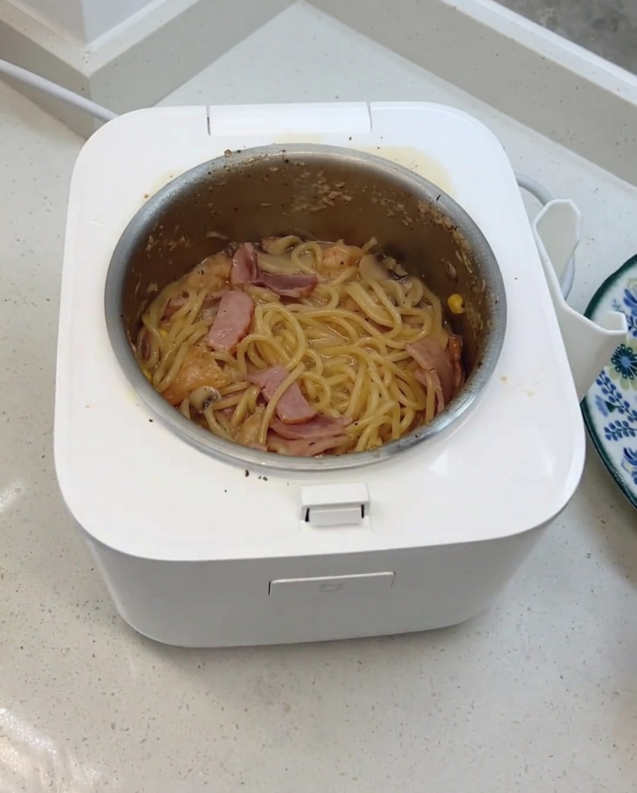 Gotowe kremowe spaghetti z grzybami mieszane z dodanym serem i kostkami nabiałowymi w szybkowarze.