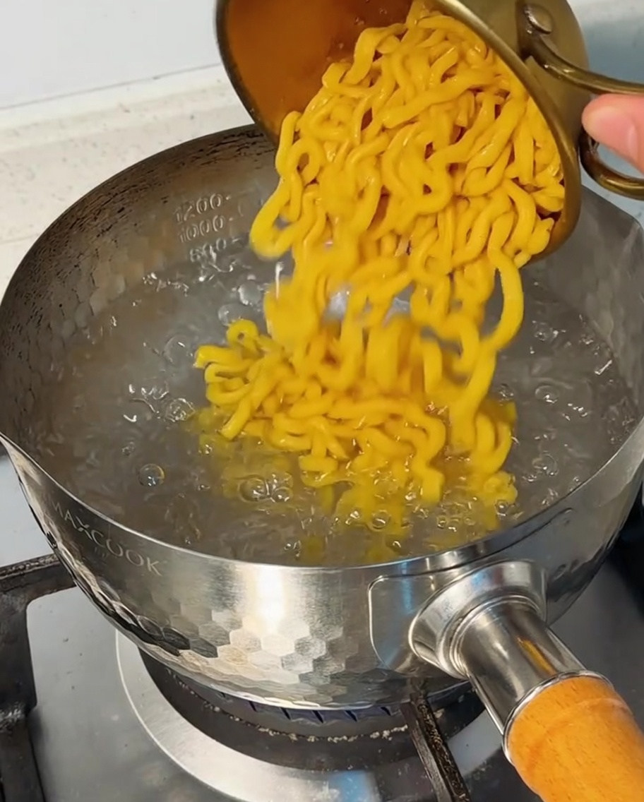 Makaron wsypywany do garnka z wrzącą wodą.