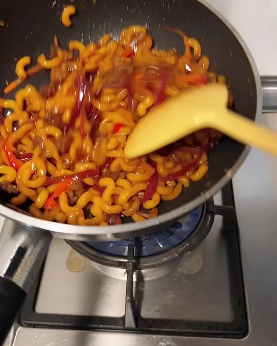 Makaron mieszany na patelni z rozpuszczającym się serem.