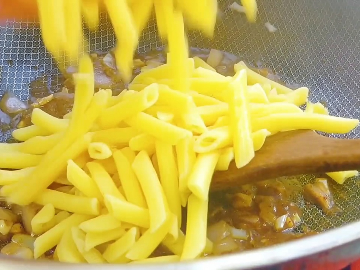 Ugotowany makaron penne dodawany do woka z bazą sosu pieprzowego.
