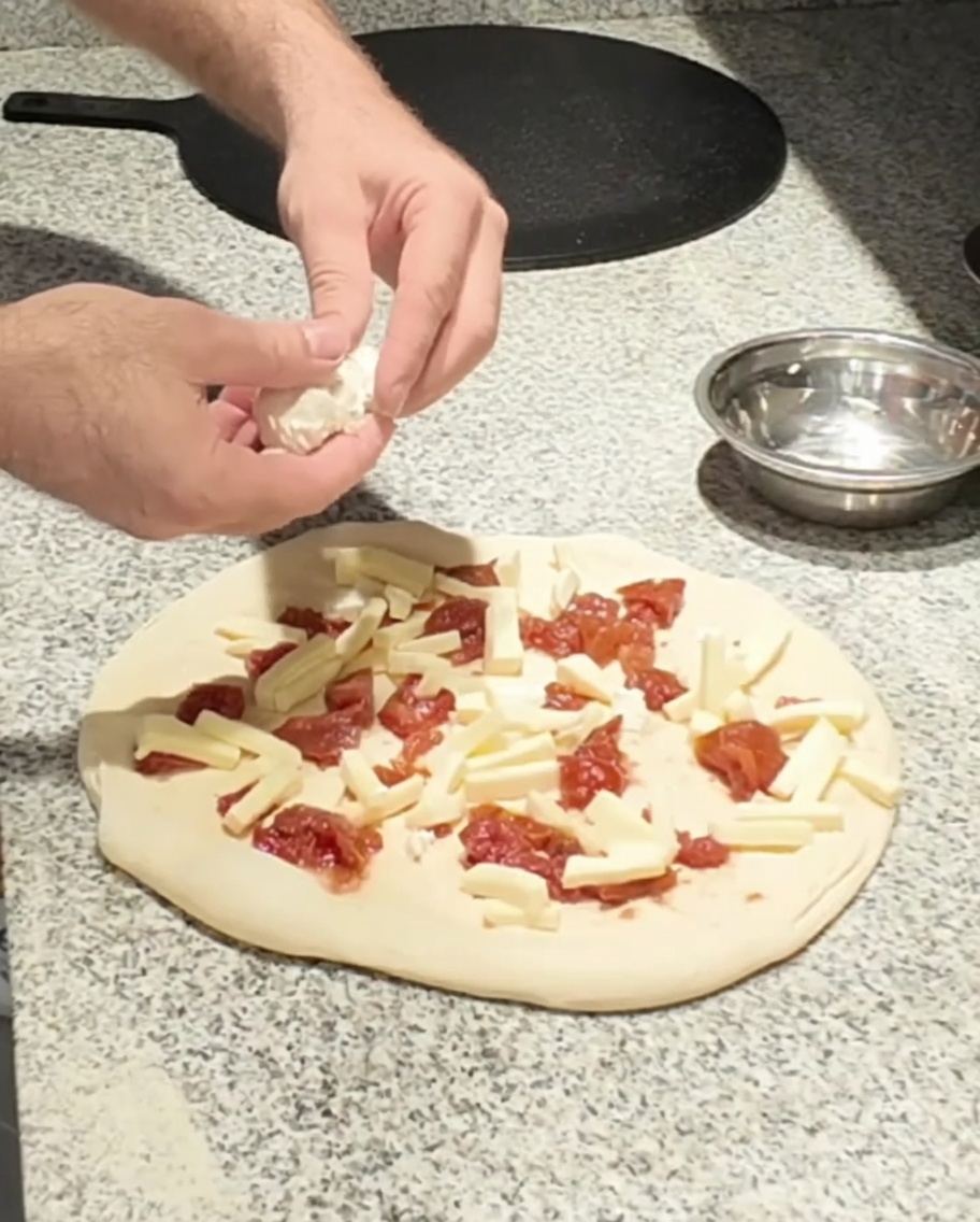 Świeży kozi ser umieszczany na pizzy.