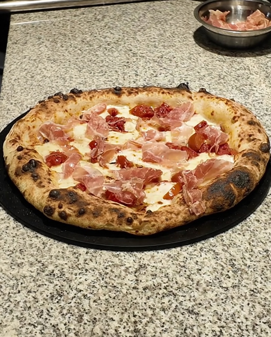Zbliżenie na świeże zielone listki tymianku posypywane na upieczoną pizzę.