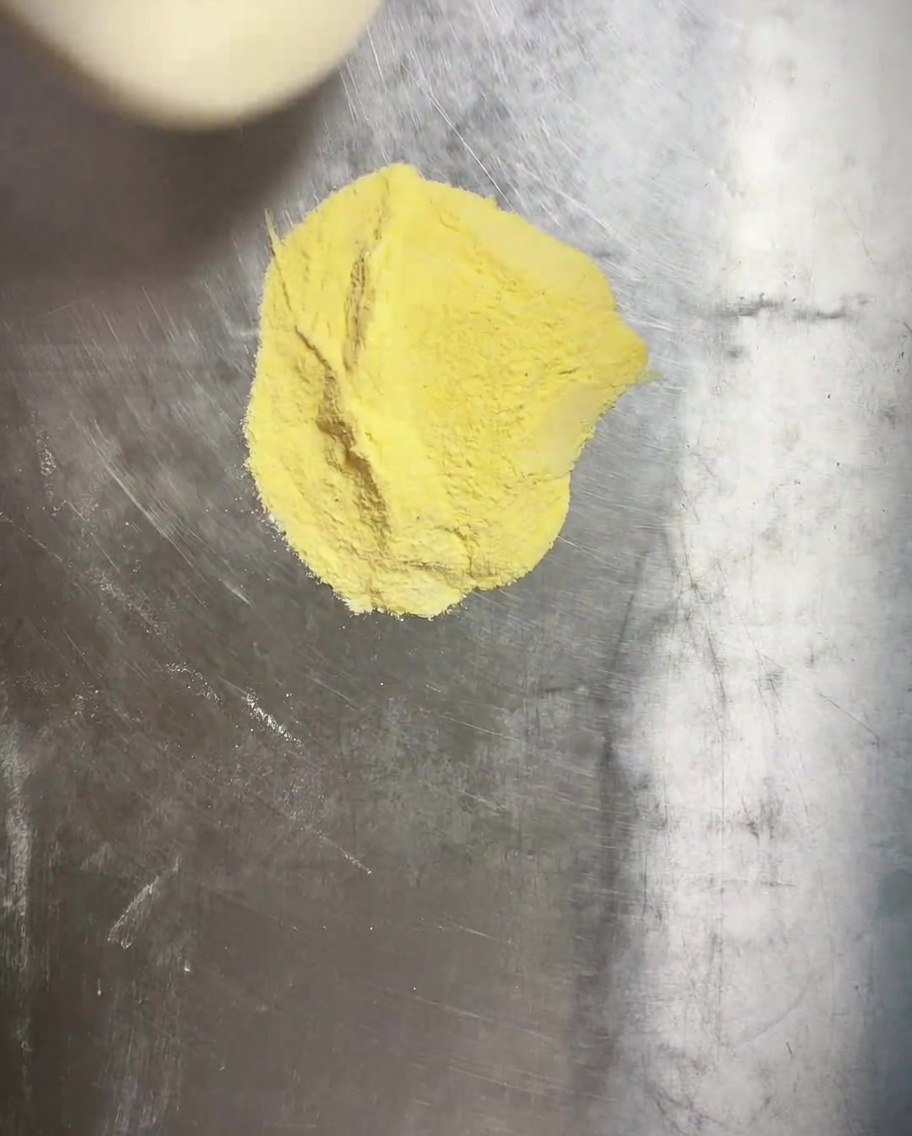 Ciasto na pizzę układane w okrągłej formie wysypanej mąką kukurydzianą.