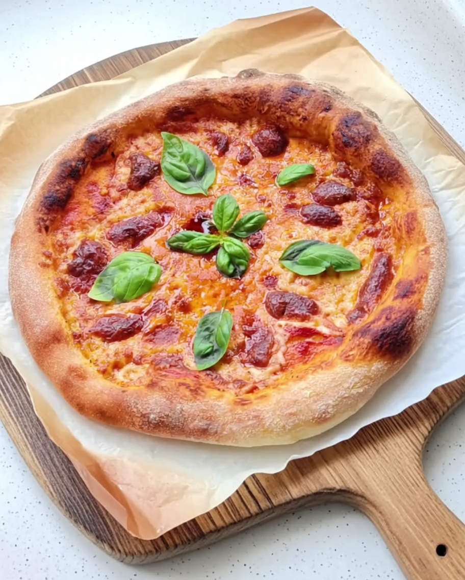 Włoski sos pomidorowy rozprowadzany równomiernie na okrągłym spodzie pizzy.