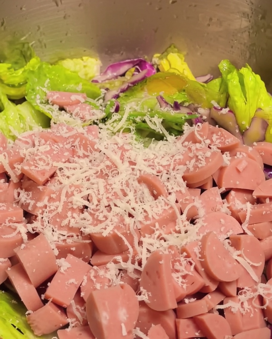 Drobno pokrojona szynka i starty parmezan dodawane do sałatki warzywnej.