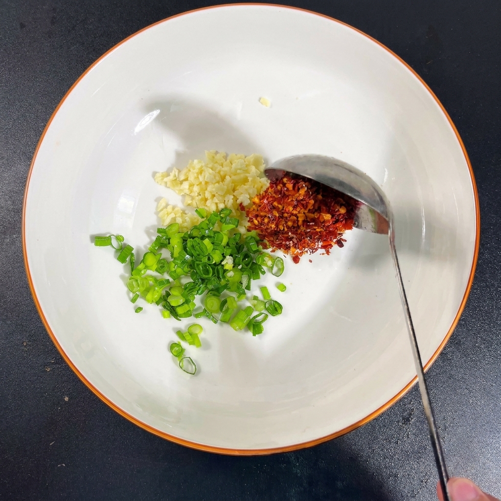 Miska z czosnkiem, szczypiorkiem, solą, MSG, płatkami chili i sosem sojowym.