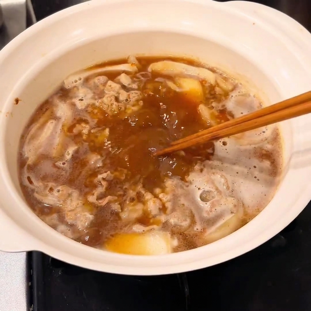 Kostka curry mieszana w garnku w celu uzyskania gęstego sosu.