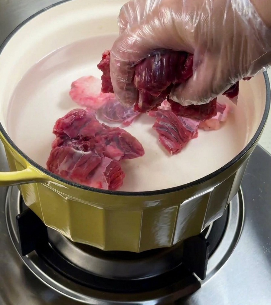 Mostek wołowy blanszowany w garnku z wodą i dodatkami aromatycznymi.