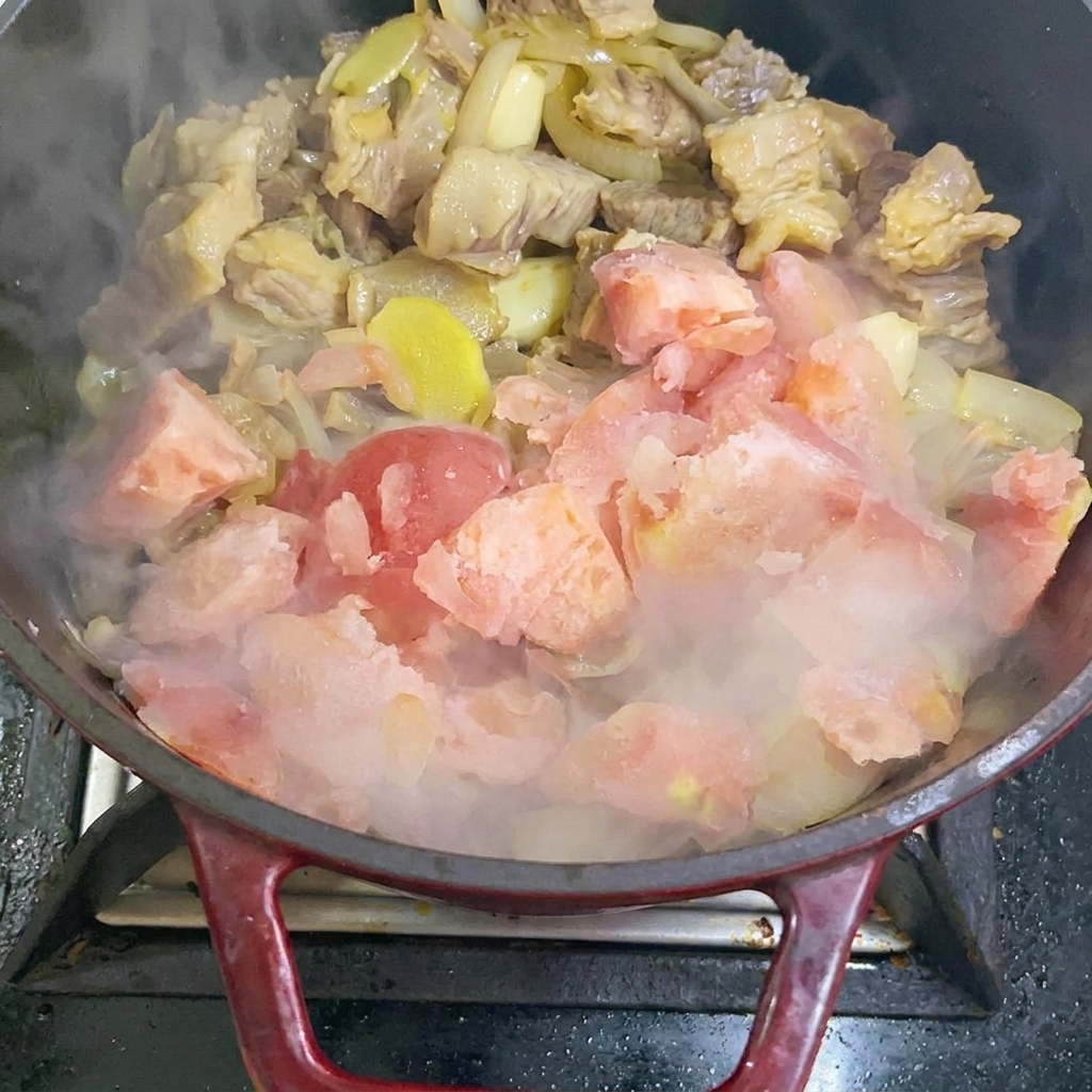 Dodawanie kawałków mrożonych pomidorów do garnka.