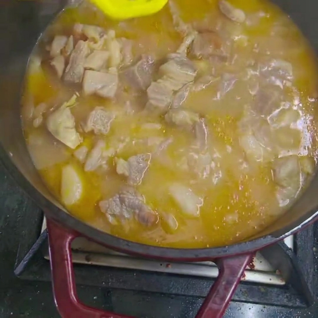 Dodawanie kawałków marchewki i ziemniaków do gotującego się gulaszu.