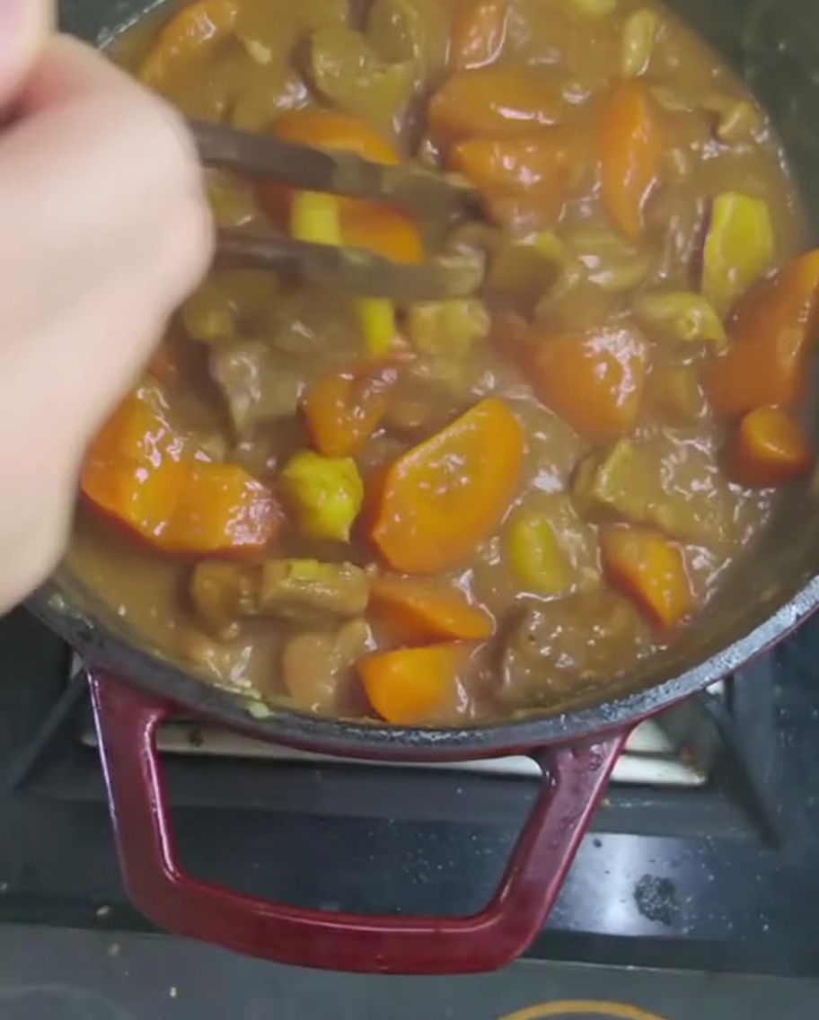 Mieszanie gęstego sosu curry drewnianą łyżką.