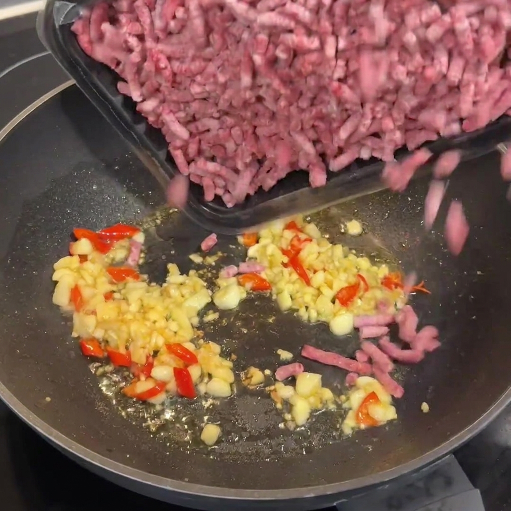 Surowa mielona wołowina Wagyu dodawana do gorącego woka z czosnkiem i chili.