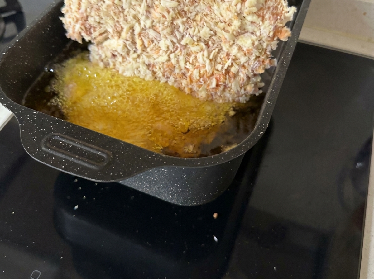 Panierowany kotlet wołowy smażący się na patelni w gorącym oleju.