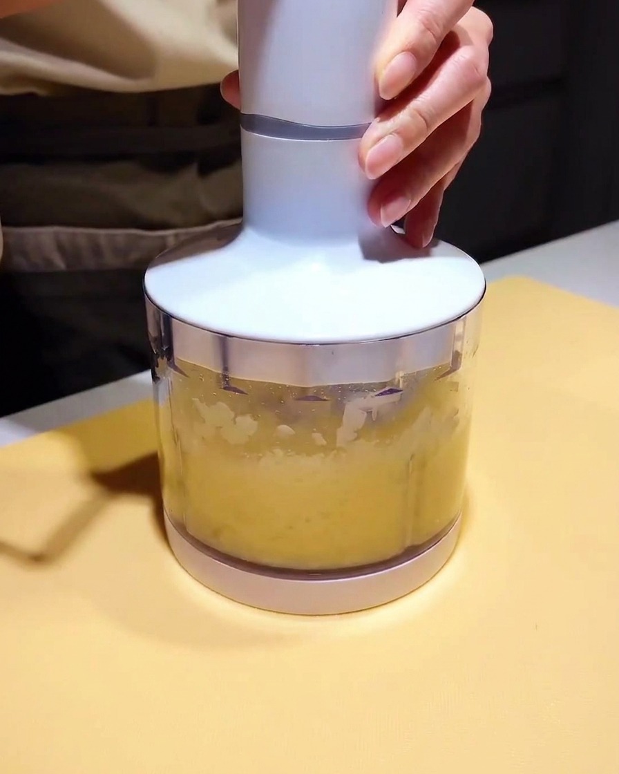Mały blender wypełniony jasnym puree i ciemną bazą marynaty, gotowy do blendowania.