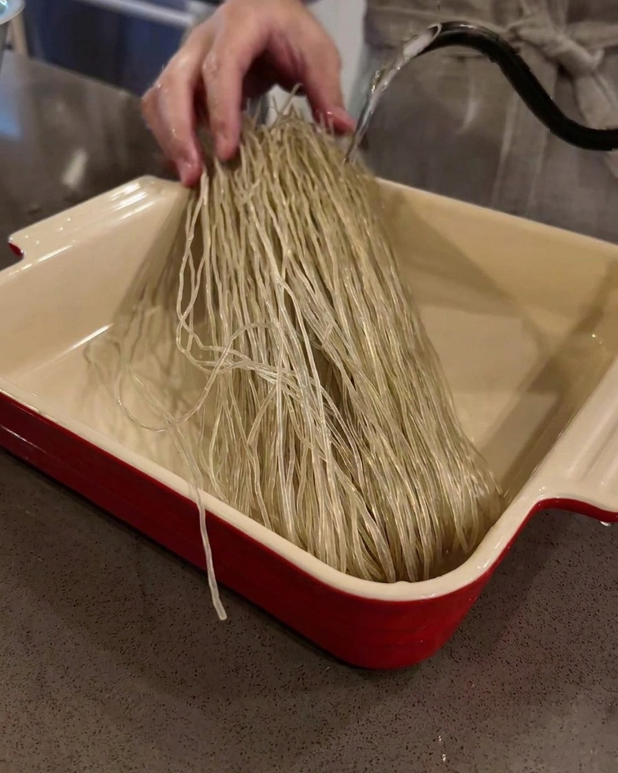 Suchy makaron szklany namaczany w naczyniu z ciepłą wodą.